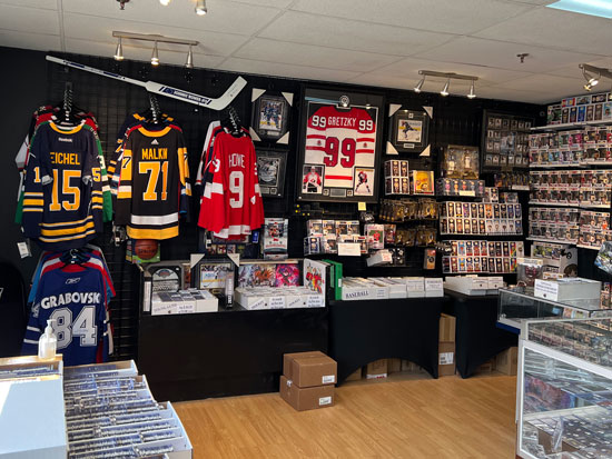 In side our store image with a focus on the wall showcasing hung jerseys, framed artwork and FUNKO Pops