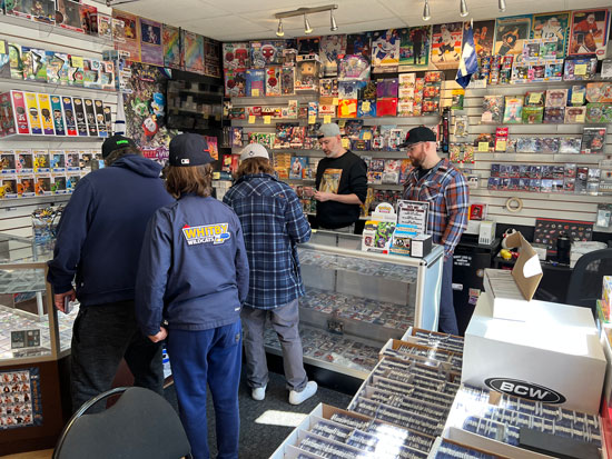 In side our store image with a focus on a father and two children buying baseball cards on a Saturday morning